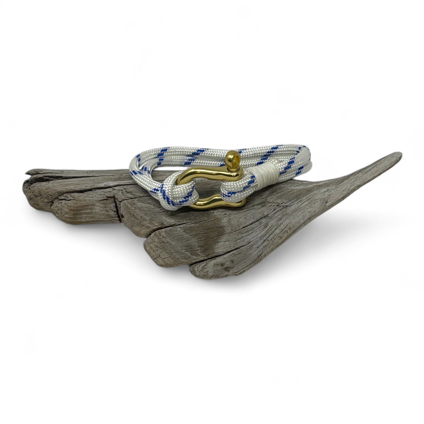 Nautical bracelet with blue and white rope and gold clasp on a piece of driftwood.