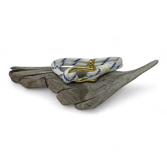 Nautical bracelet with blue and white rope and gold clasp on a piece of driftwood.