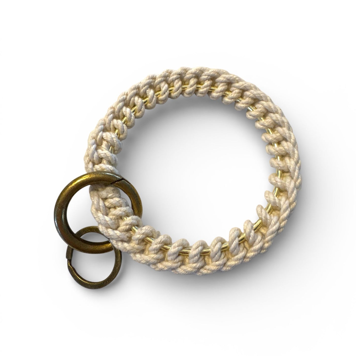 Brass ring with braided beige cord on a white background